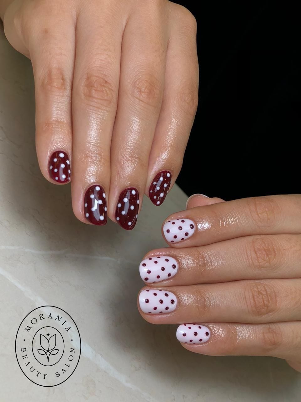 Manicura de lunares en borgoña y blanco sobre uñas cortas redondas, MORANIA Lima.